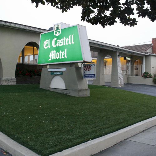A campus building with a curved entrance and a green banner held up by people, likely a protest or event outside.